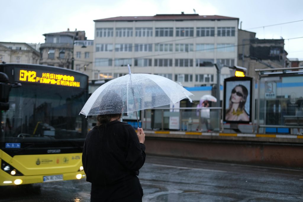 Person with umbrella on rainy city street, reflecting on long-term trauma.