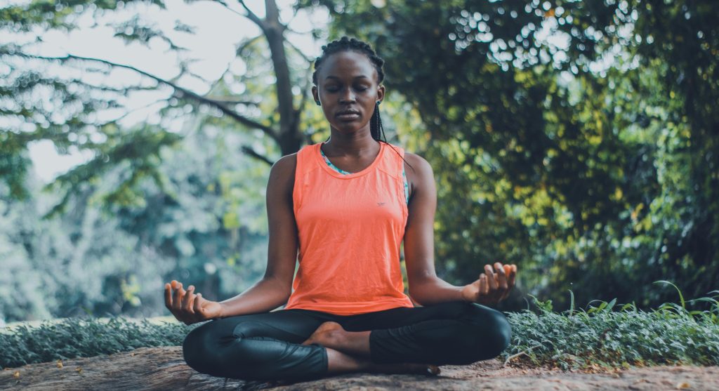 Woman meditating in a forest, embracing nature as a way to cope with and heal from past trauma.
