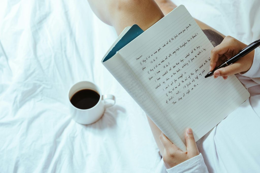 Person sitting in bed, writing in a journal to manage and dealing with triggers.