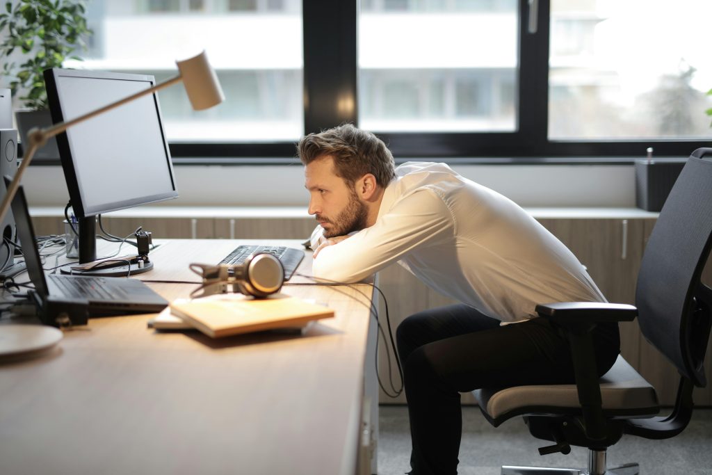 Man feeling the emotional effects of cyberbullying, exhausted at his desk.