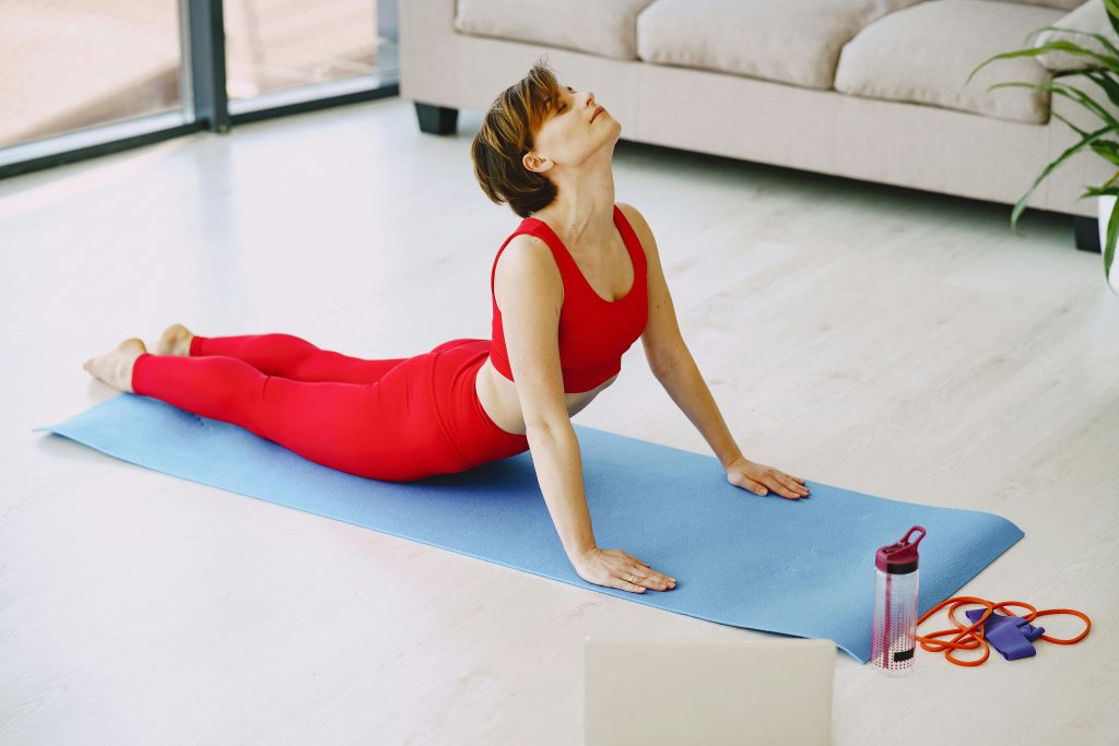 Woman practicing yoga in her living room, showcasing the connection between mind and body.