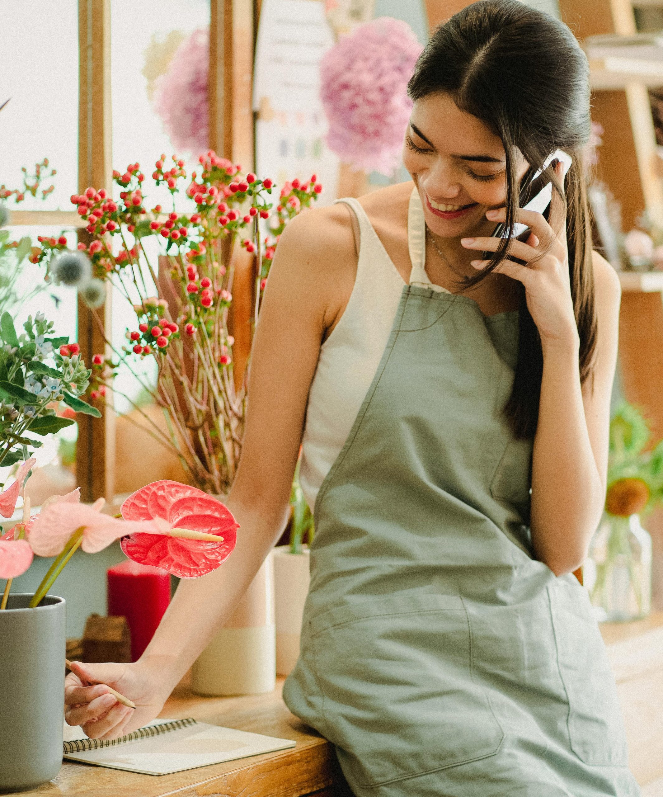 Woman on the phone, smiling and surrounded by flowers, symbolizing compassion and personal connection