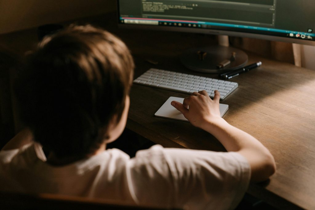 Young person working on a computer, highlighting the emotional effects of cyberbullying.