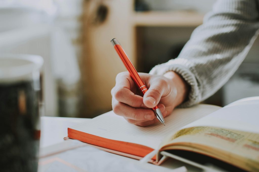 Person writing in a notebook during mental illness awareness week.