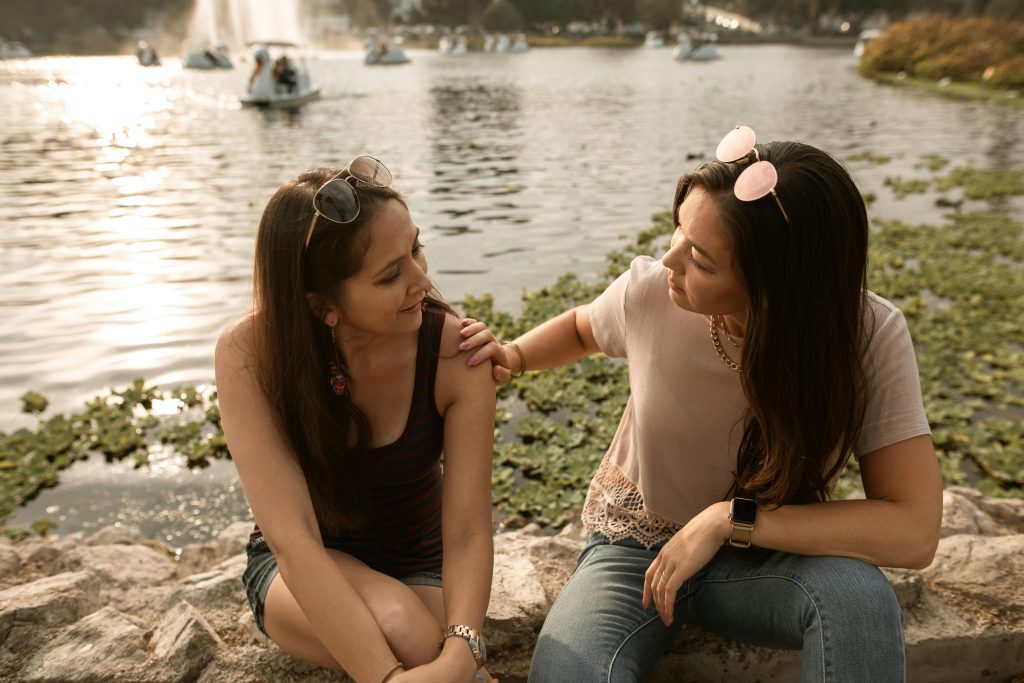 Two friends connecting by a lakeside, symbolizing support for invisible disabilities.