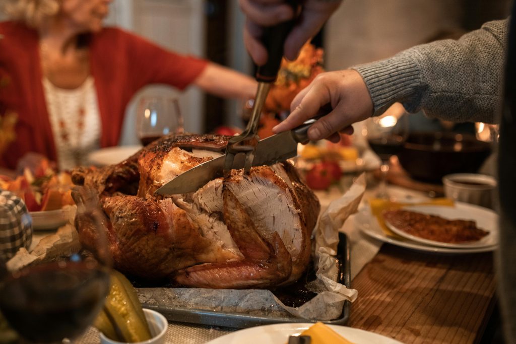 Carving turkey during a thanksgiving meal, depicting holiday stress management.