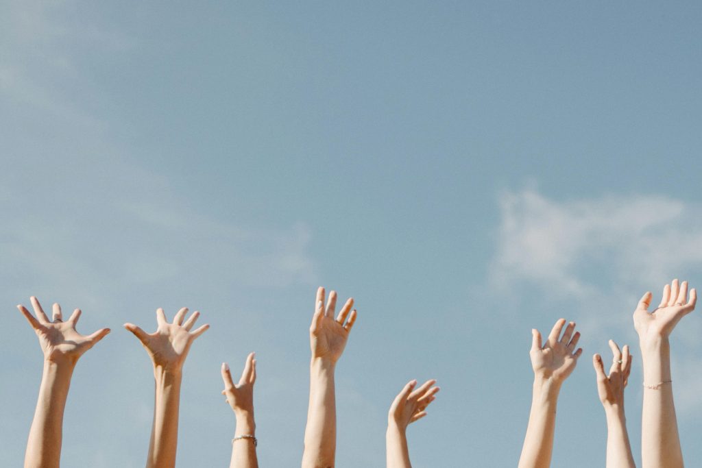 Addiction awareness represented by raised hands against a clear sky.