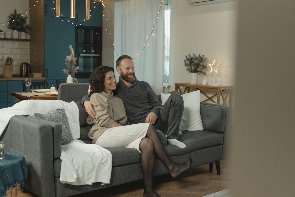 A couple enjoys a cozy moment together on a sofa, reflecting a serene atmosphere beneficial for relationship growth, depicted in a comfortably decorated living room.