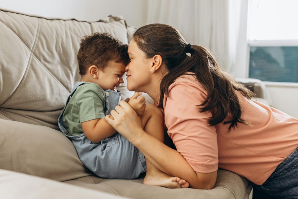 A mother tenderly touches noses with her young son, symbolizing the positive influence of nurturing relationships on overcoming childhood trauma in adulthood.