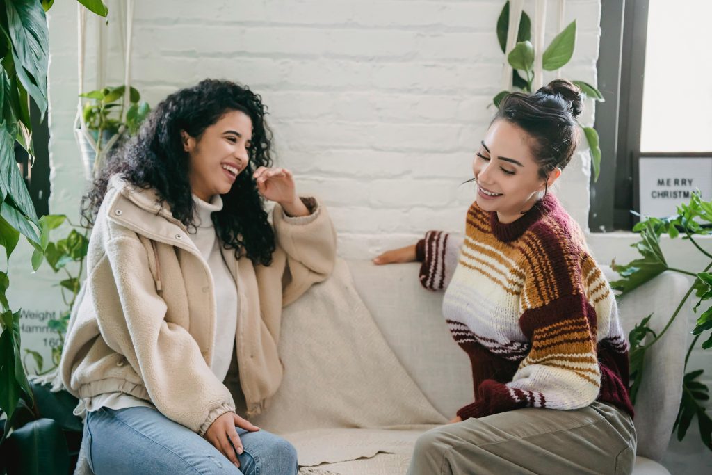 Two friends share laughter in a cozy indoor setting, highlighting the importance of social connections in managing seasonal affective disorder (sad).