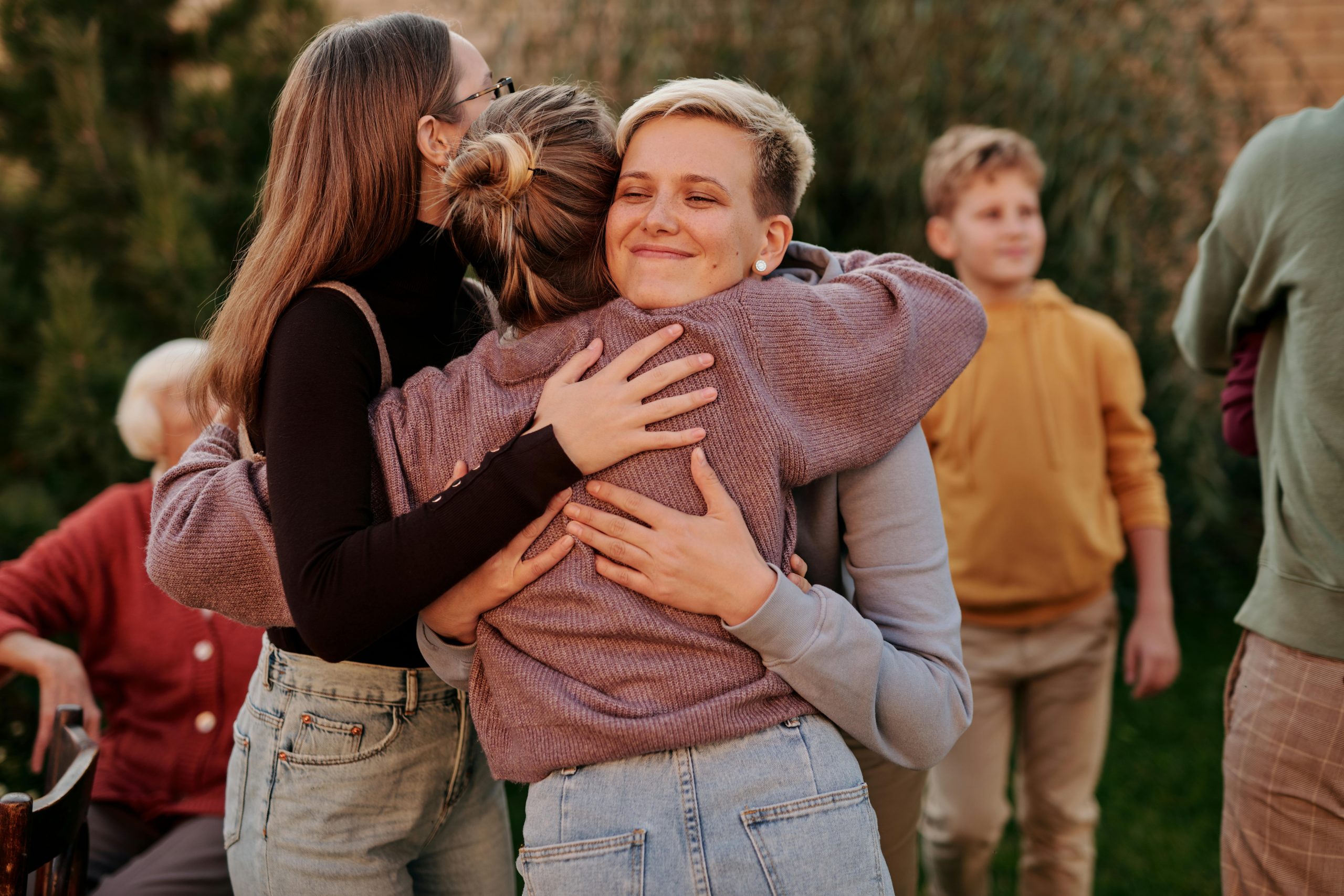 Friends embracing in a group hug outdoors during a joyful reunion.