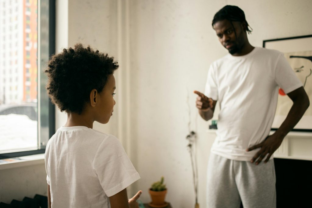 A serious discussion between a father and his young son, highlighting a moment that could impact their relationship dynamics and emotional well-being.