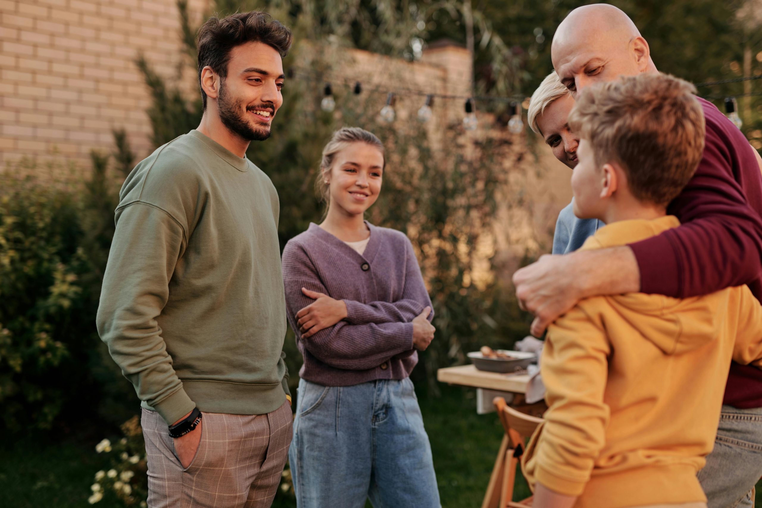Supportive-Family-Gathering A family standing together in a backyard, smiling and engaging in a supportive conversation, symbolizing connection and understanding.