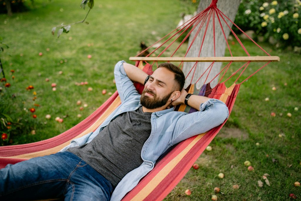 A man relaxing in a hammock outdoors, looking peaceful, symbolizing recovery and peace following trauma and dissociation experiences.