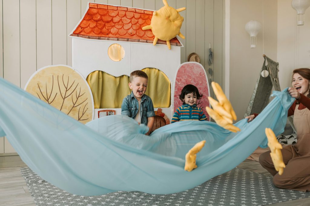 A joyful indoor scene with two children and an adult playing in a whimsical playhouse, symbolizing engaging and therapeutic family activities as a part of treatment for postpartum psychosis.