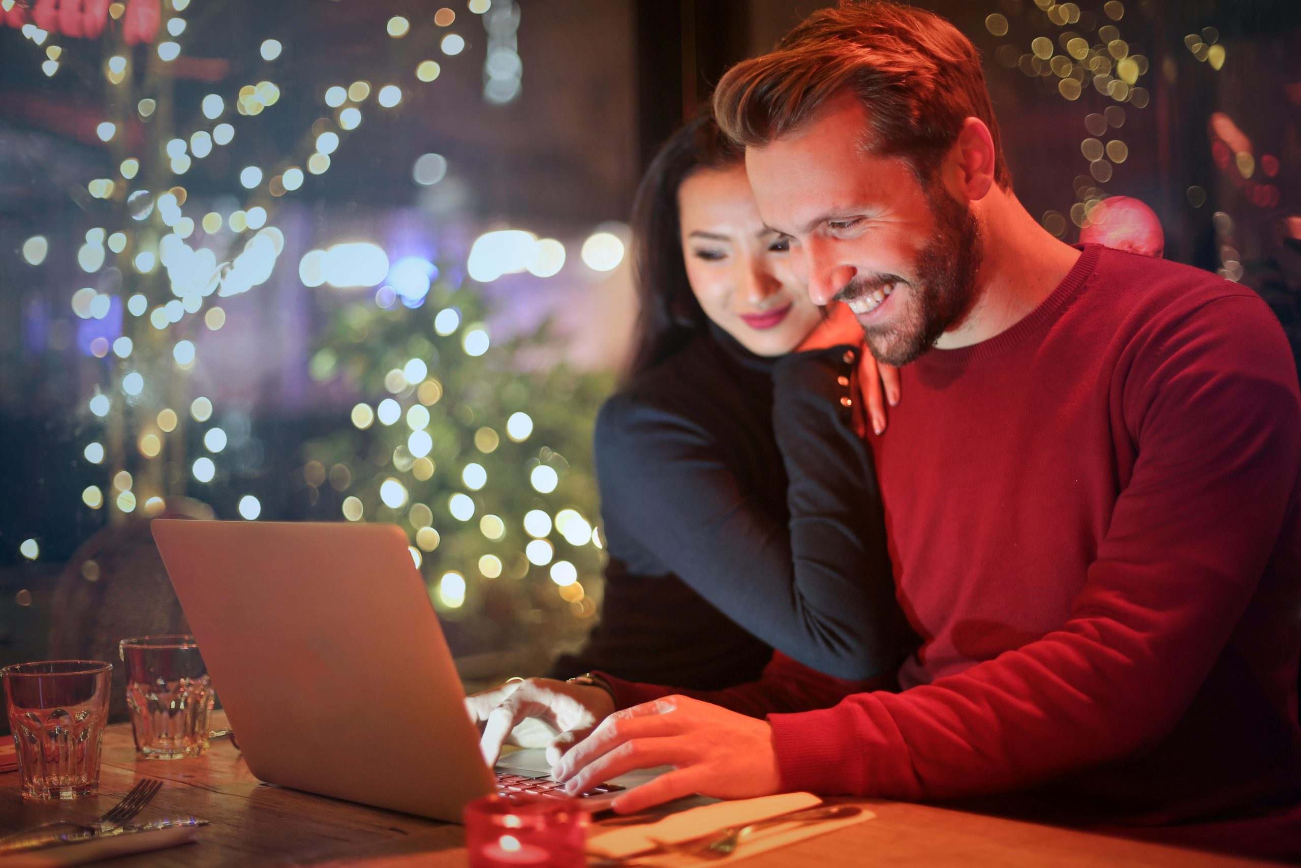 Smiling couple enjoying time together while looking at a laptop in a warmly lit setting