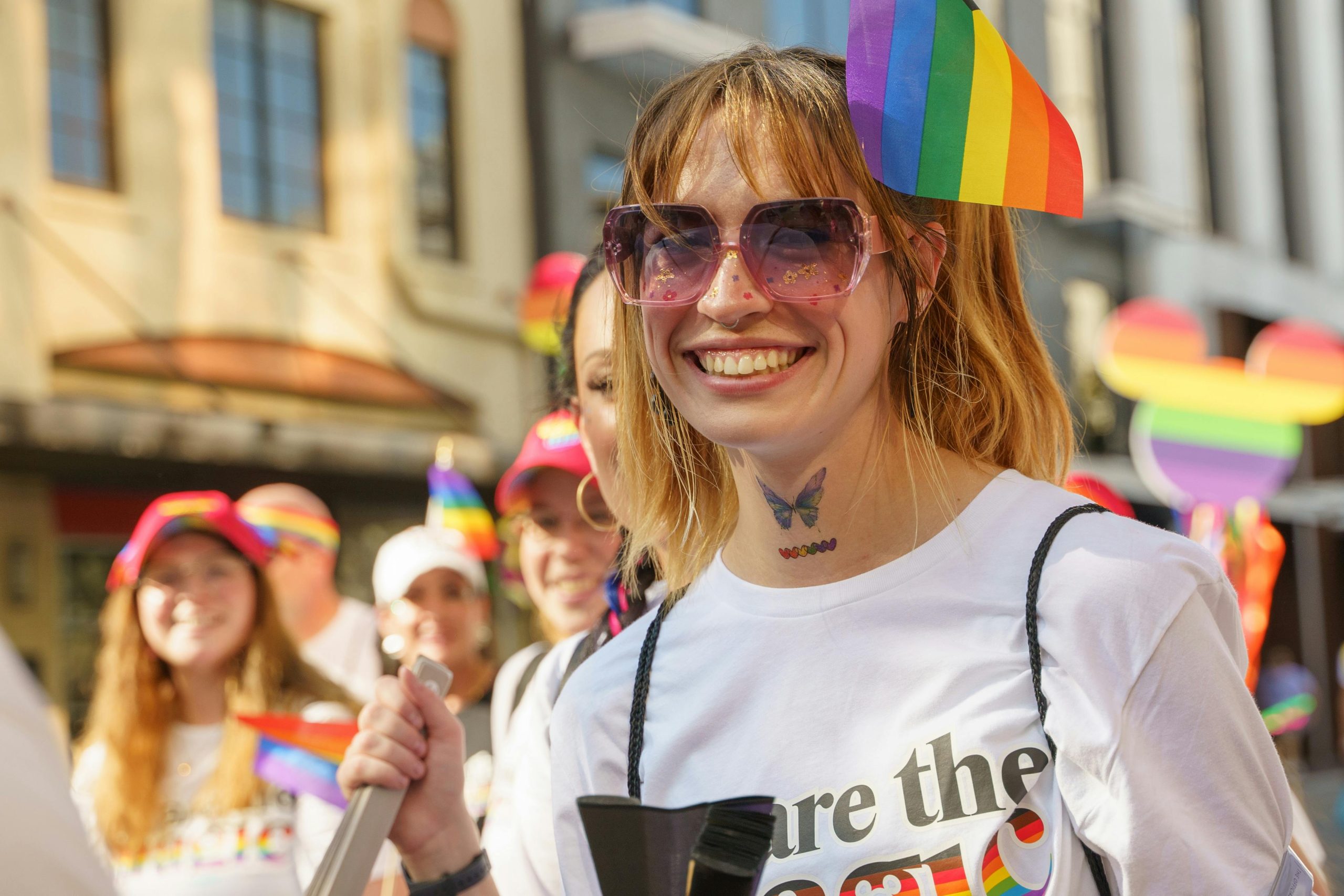 Lgbtq-Therapy-Mindshift-Safe-Space Smiling person wearing a rainbow flag and sunglasses at a pride parade
