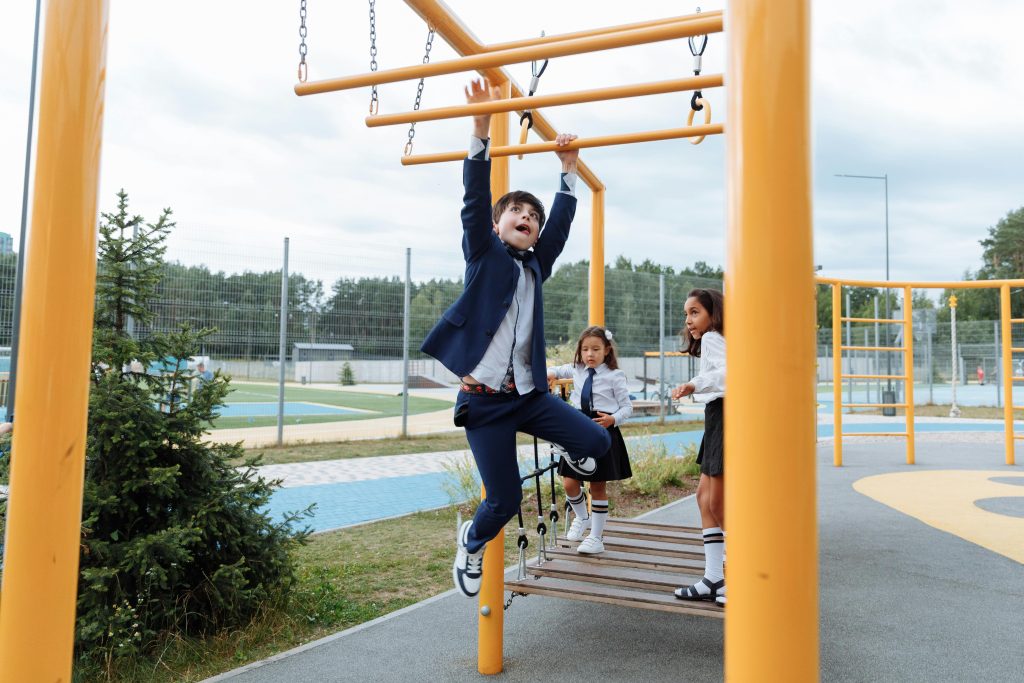 Symbolic childhood trauma captured by a child in formal clothes struggling on monkey bars while others watch at a school playground