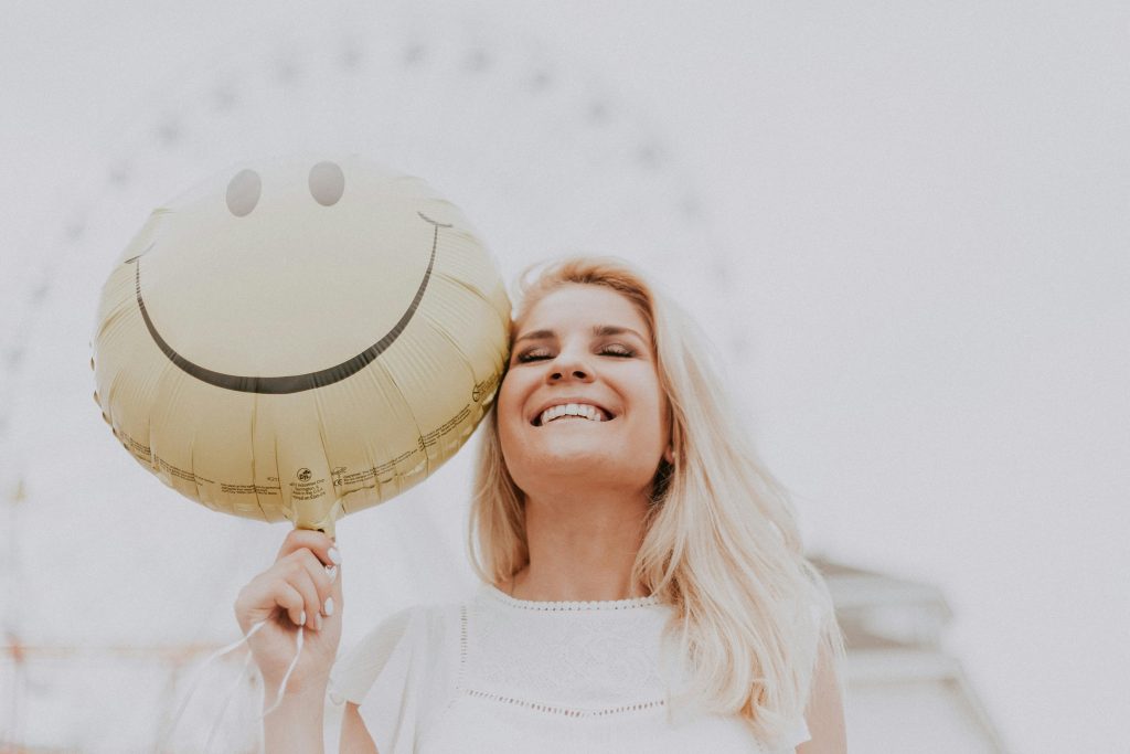 What is anxiety disorder concept shown through a smiling woman holding a happy face balloon, symbolizing masked emotions