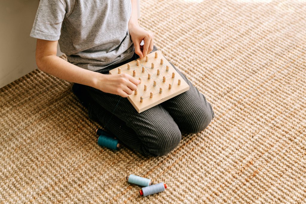 Child using threading board with spools of thread.