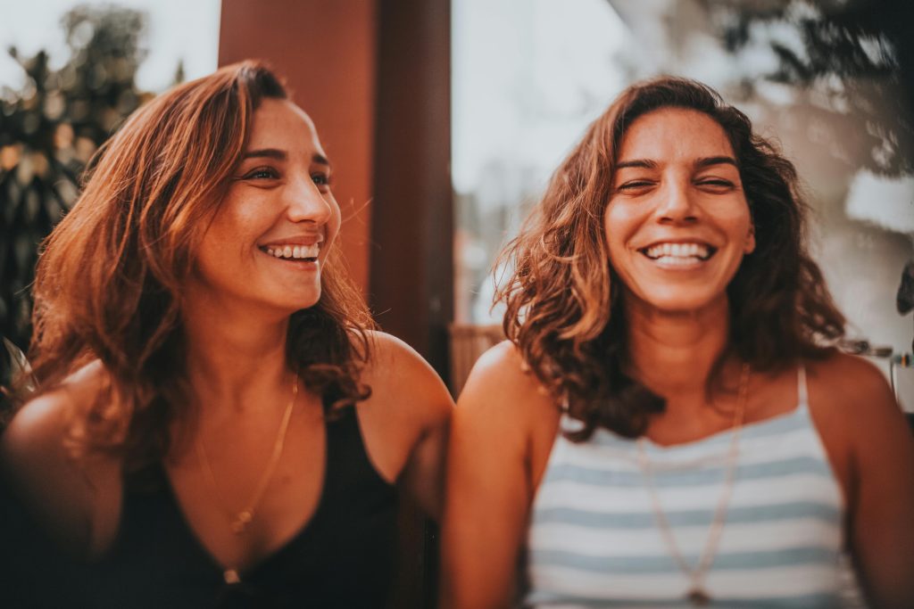 Two women smiling and laughing together during a trauma-informed therapy session.