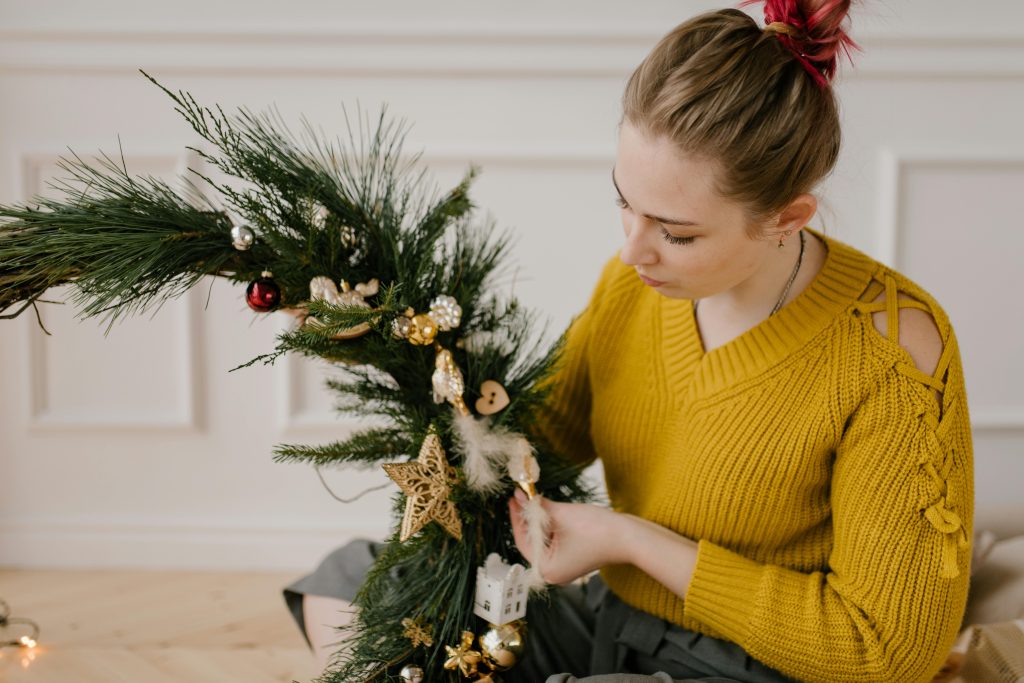 Woman decorating wreath for christmas amid overwhelming expectations.
