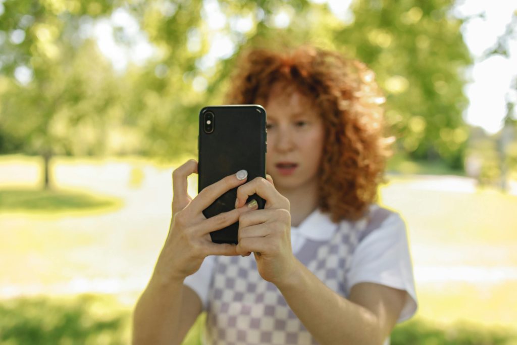 Redhead taking a selfie in nature, social media break during holidays.