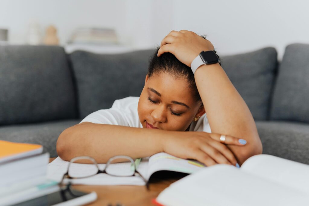 Student resting head on arm over open book, showing why am i always so tired while studying