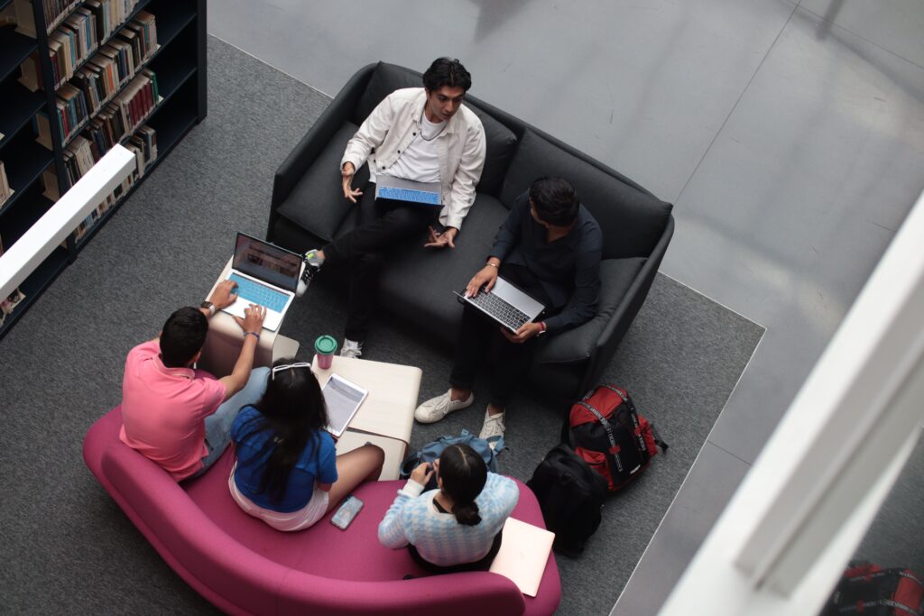 Students collaborating with laptops in a study area, demonstrating time management for students through group planning and organization